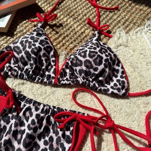 Sexy leopard print bikini set with red tie details on a stylish vacation background