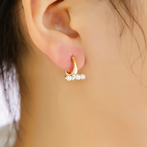 Gros plan sur des créoles dorées avec perles blanches et zircon sur l'oreille du mannequin