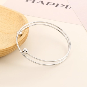 Macro detail of silver double-layered steel ball cuff bracelet on warm wooden background