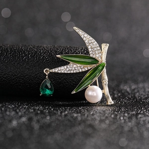 Macro shot of bamboo leaf brooch with green enamel, crystals, pearl and emerald drop