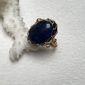 Detailed macro shot of blue tiger eye gemstone wrapped in handcrafted 14k gold wire