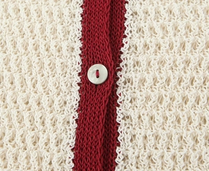 Detailed close-up of hollow knit fabric with red and white patterns and button details