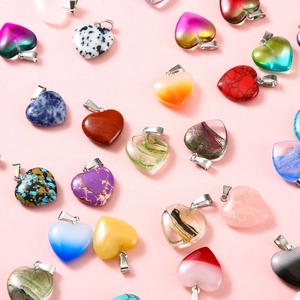 Collection of colorful 20mm heart-shaped crystal stone pendants on pink background