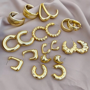 Detailed view of assorted gold geometric earrings on elegant champagne silk fabric