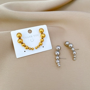 Macro shot of curved stainless steel earrings with gradient beads in gold and silver finish