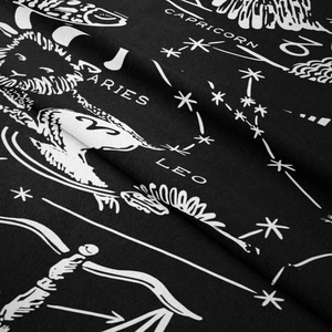 Gros plan sur tissu noir avec motifs blancs des constellations du Capricorne et du Bélier