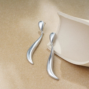 Macro shot of long silver teardrop earrings with a minimalist sleek metallic finish