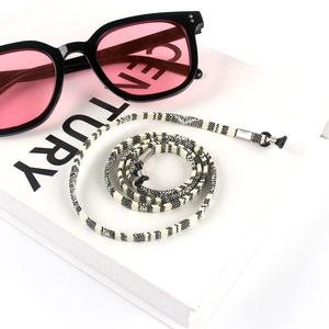 Close-up of black and white woven eyewear strap on book with pink lens sunglasses