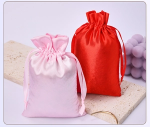 Detailed view of pink and red satin drawstring gift bags on a marble display base