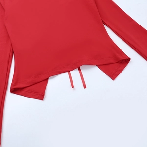 Dettaglio del top in pizzo rosso con fiocco decorativo e orlo asimmetrico irregolare