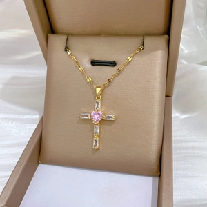 Detail of gold cross necklace with pink heart gemstone and zircon in elegant gift box