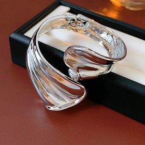 Macro view of a silver irregular twisted metal open bangle with mirror polish finish