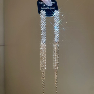 Macro detail of silver long tassel earrings with sparkling rhinestones and woven pattern