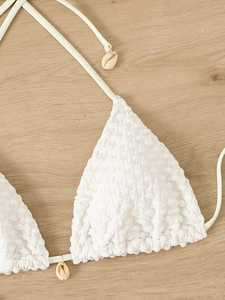 Detail of white smocked bikini top with triangle cups and natural shell charms
