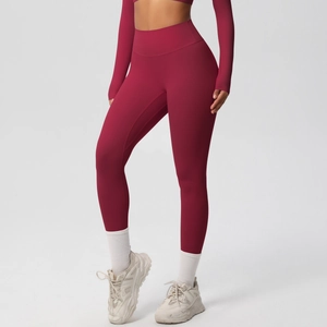 Detail view of high-waist seamless yoga leggings and long sleeve crop top in dark red color