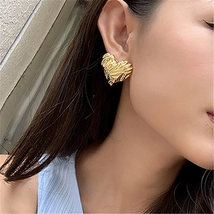 Golden heart earrings with textured lava finish worn by a model in a stylish side view