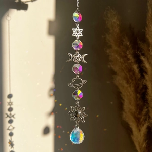 Detailed view of crystal sun catcher with metal moon star pendants and rainbow refraction