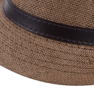 Détail de la texture en paille tressée et du ruban en cuir marron sur le chapeau fedora