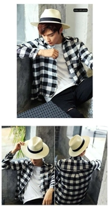 Dettaglio di un cappello fedora in paglia bianco crema con nastro nero decorativo