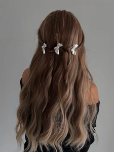 Gros plan de barrettes nœuds argentés avec perles sur cheveux ondulés
