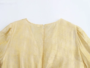 Gros plan d'une robe jaune en jacquard avec col rond, manches bouffantes et zip invisible