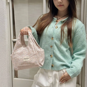 Close-up of pink floral canvas lunch bag with brand label held by a model