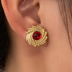 Vintage gold spiral round earrings with red gemstone inlay shown on a model