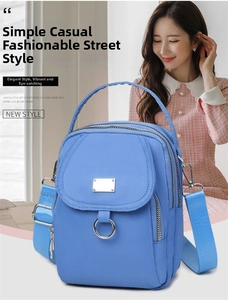 Detail of light blue nylon crossbody bag with multi-zipper layers and adjustable strap