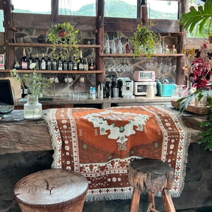 Bohemian style knitted throw blanket with fringe edge on a rustic wooden bar counter