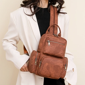 Detailed view of brown PU leather backpack texture and vintage metal zipper pockets