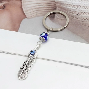 Portachiavi a piuma d'argento con perline occhio del male blu su sfondo bianco