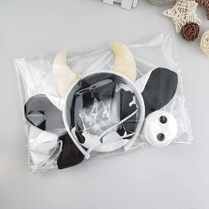 Detailed view of plush cow costume set with animal ears and spots in plastic packaging