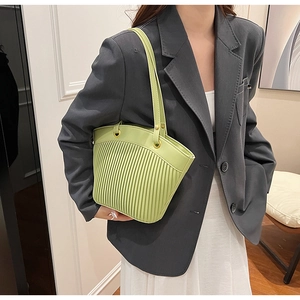 Detail of light green pleated tote bag with vertical stripes and golden metal eyelets