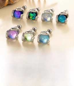 Detailed view of silver snake-shaped cartilage studs with iridescent moonstone spheres