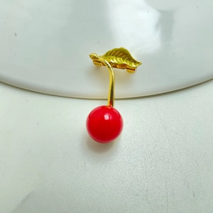Detailed view of a cherry brooch with red enamel fruits and a golden alloy stem