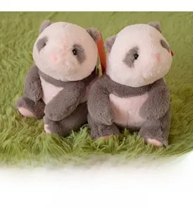 Close-up of two plush panda toys sitting on a soft green rug in a cozy home setting