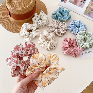 Detailed close-up of floral fabric scrunchies in red, yellow, and blue pastel colors