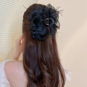 Pince à cheveux fleur en organza noir élégante portée par un modèle aux cheveux bouclés