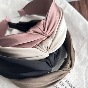 Detailed view of stacked fabric headbands with knot detail in pink, beige, black, and brown