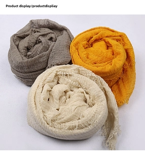 Close-up of lightweight Bali yarn scarves with fringed edges in grey, yellow and cream