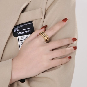 Detailed view of wide gold layered gear ring with inset cubic zirconia on person hand