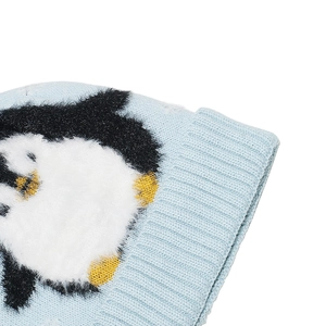 Close-up of light blue knit hat featuring fluffy penguin embroidery and ribbed cuff