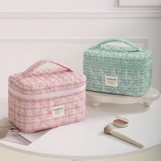 Detail of pink and mint green tweed makeup bags with woven texture and handle