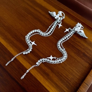 Detailed macro view of silver Pegasus tassel earrings with crystal stars and chains