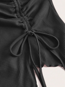 Detailed macro view of black ribbed knit fabric featuring drawstring ruching and bow detail