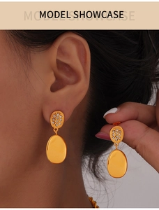Detail of gold-plated double-layer oval earrings with sparkling white rhinestones on model
