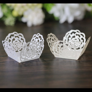 Detail view of laser-cut rose lace cupcake wrappers in white and beige art paper