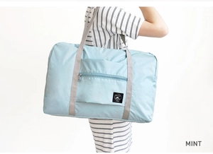 Side view of large mint green folding travel bag worn on shoulder for capacity display