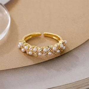 Detail of adjustable gold ring featuring white pearls and baguette cut zirconia accents