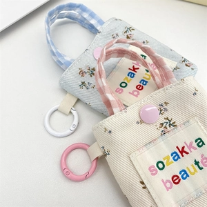 Detailed macro view of floral canvas mini pouch with embroidered letters and snap button